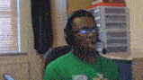 a man wearing headphones and a green shirt is sitting in front of a window