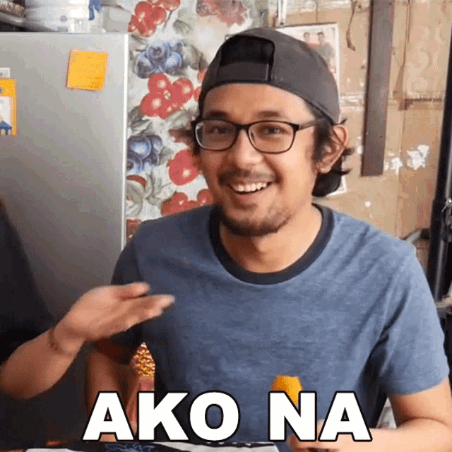 a man wearing glasses and a baseball cap is smiling and says ako na