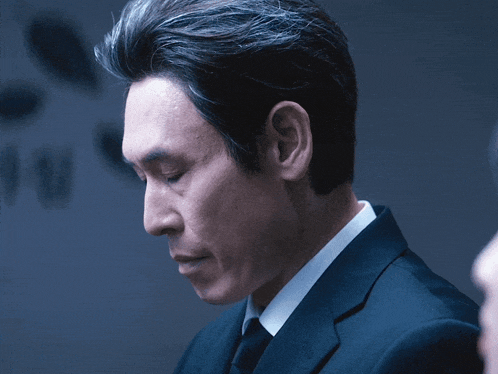 a man in a suit and tie is looking down at something
