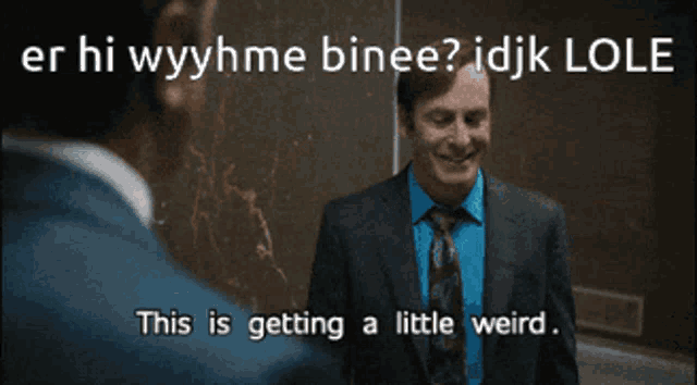 a man in a suit and tie talks to another man in a blue shirt