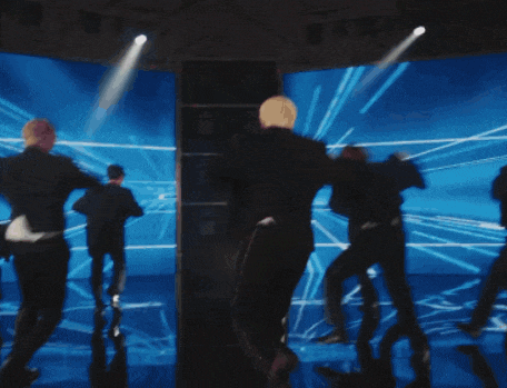 a group of men are dancing on a stage with a blue background