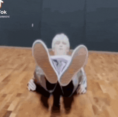 a person is sitting on a wooden floor with their feet up in the air .