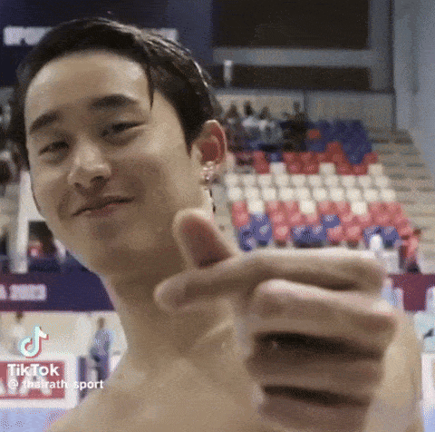 a young man without a shirt is making a heart shape with his hands .