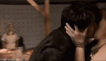 a man and a woman are kissing in front of a table .