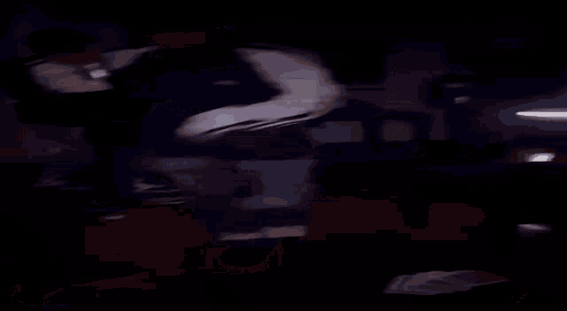 a man is laying on the floor in a dark room holding a beer .