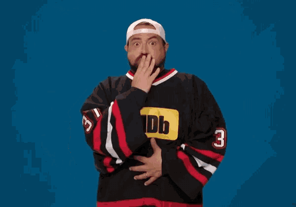 a man in a black and red jersey holds a brown paper bag over his mouth