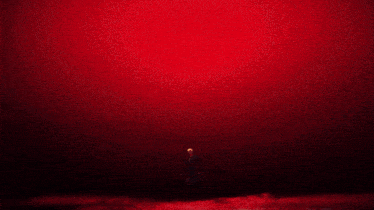 a close up of a person 's face with a red light behind it