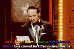 a man in a tuxedo speaking into a microphone with the words love is love is love is love is love is love