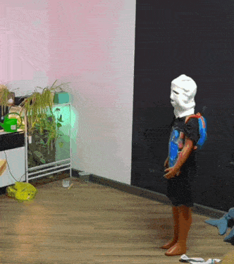 a person wearing a mask and a backpack is standing on a wooden floor