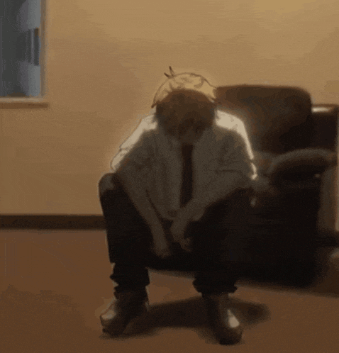a man is sitting in a chair with his head down in a room .
