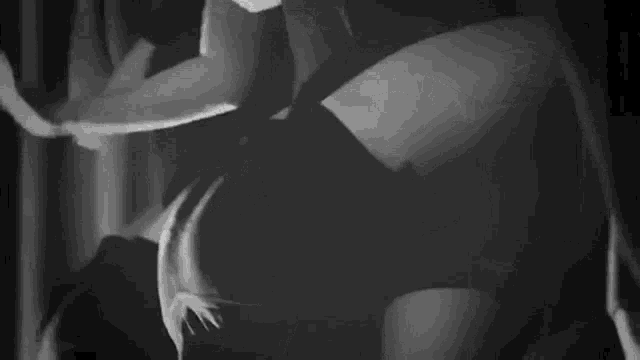 a black and white photo of a man and woman dancing in a dark room .