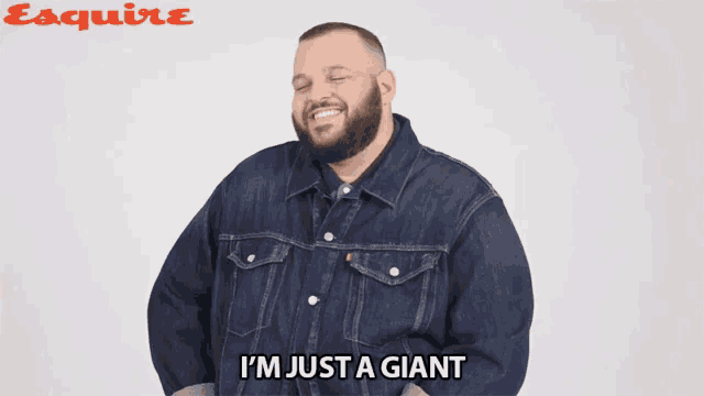 a man in a denim jacket is laughing and says i 'm just a giant
