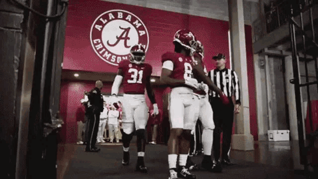 a group of alabama crimson tide football players walking into the stadium