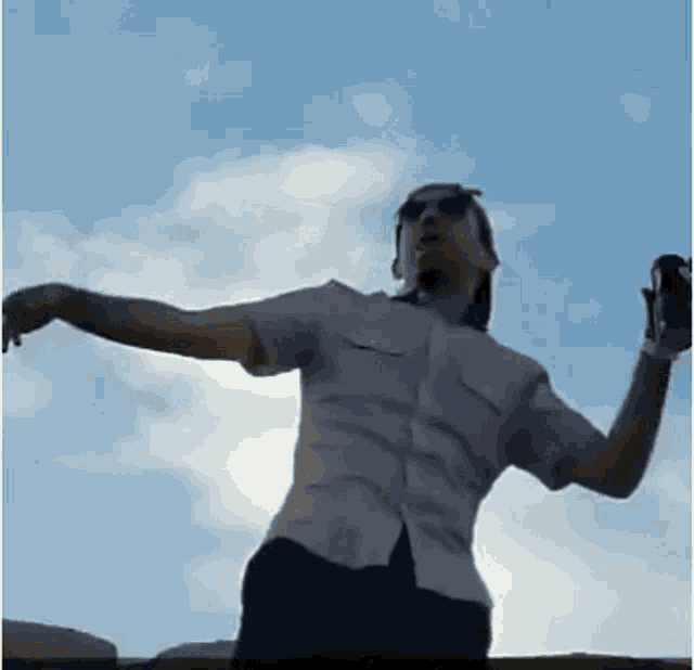 a man is standing on a ledge with his arms outstretched and a can of soda in his hand .