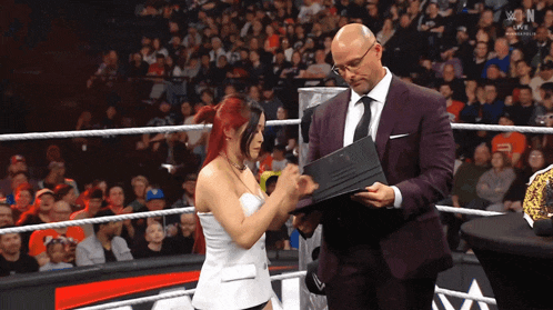 a man and woman in a wrestling ring with the word n on the bottom left