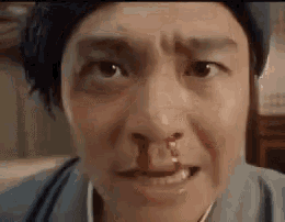 a man with blood coming out of his nose is smiling .