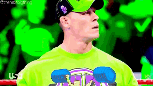 a man wearing a green shirt and a hat is standing in a boxing ring .