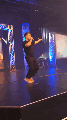 a man is standing on a stage with his arms outstretched