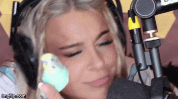 a woman wearing headphones is holding a small bird in her hand .