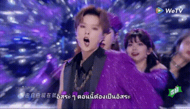 a group of people are dancing on a stage in a purple outfit .