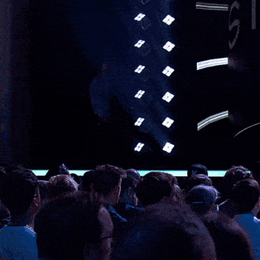 a man is walking on a stage in front of a large screen that says alan watts