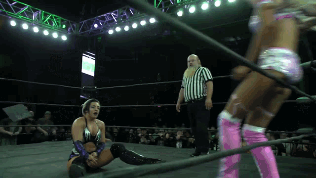 a woman in a wrestling ring with a referee watching