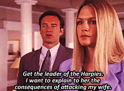 a man in a suit and tie stands next to a woman in a purple jacket who says " get the leader of the harpies "