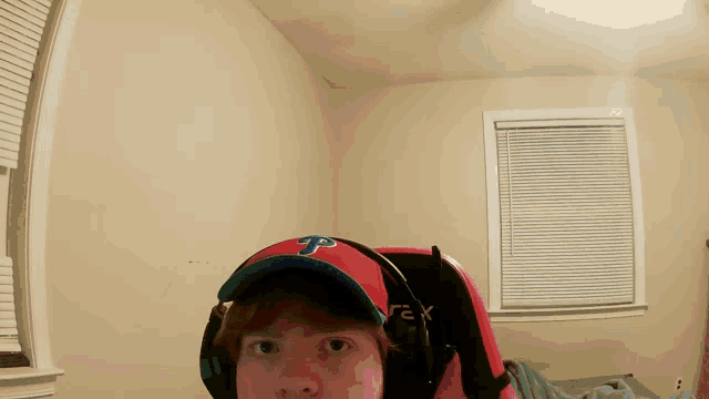 a man wearing headphones and a red cap with the letter p on it