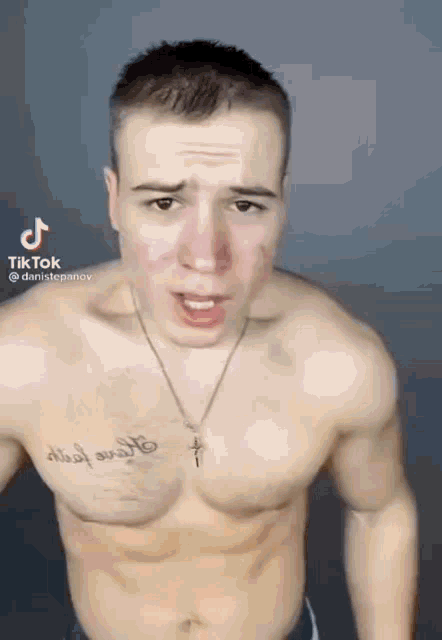 a shirtless man with a tattoo on his chest is wearing a necklace and making a funny face .