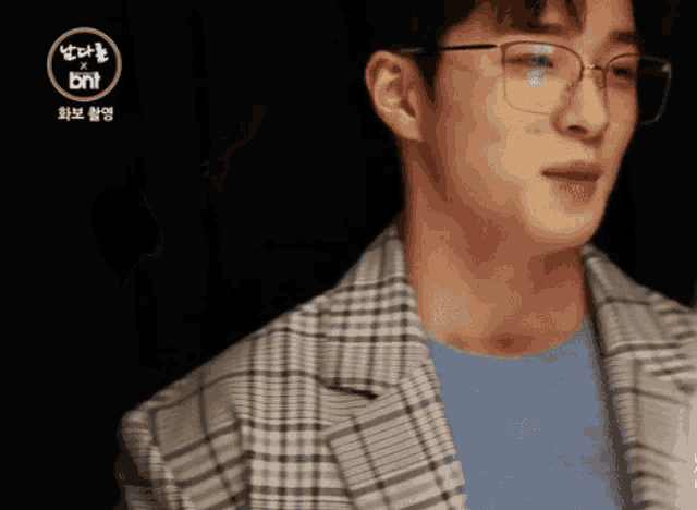 a man wearing glasses and a plaid jacket with the bnt logo in the corner