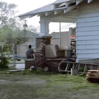 a man sits on the porch of a house next to a sign that says ' no parking '