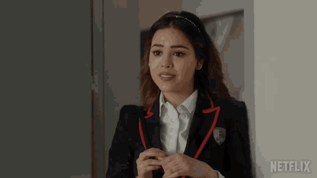 a woman in a suit is standing next to a wall with a netflix logo on it