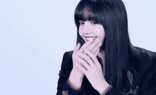 a woman with long black hair and bangs is smiling and laughing .