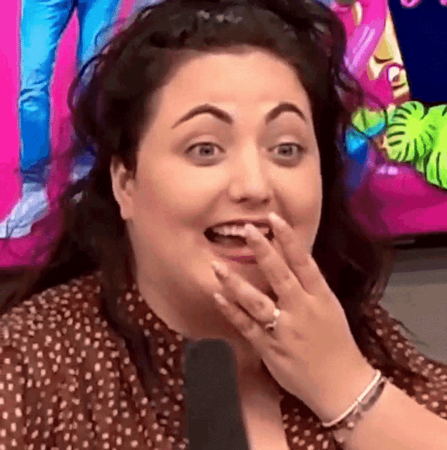 a woman is covering her mouth with her hand while sitting in front of a microphone .