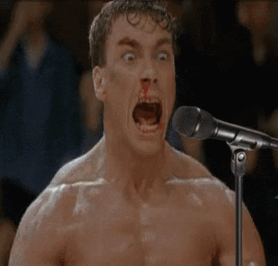 a shirtless man is singing into a microphone with his mouth wide open .