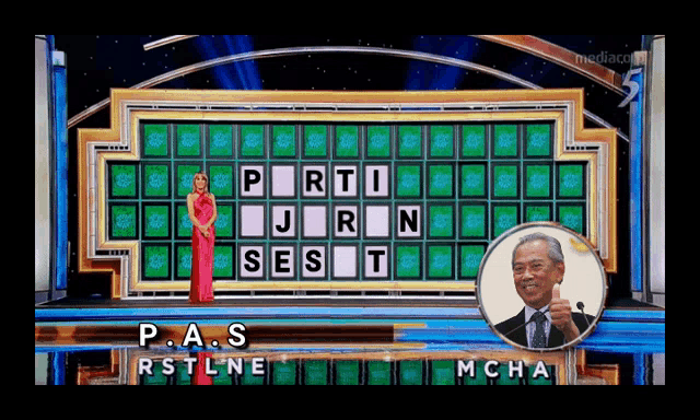 a woman in a red dress is standing in front of a wheel of fortune board