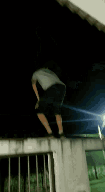 a blurry picture of a man jumping over a fence at night