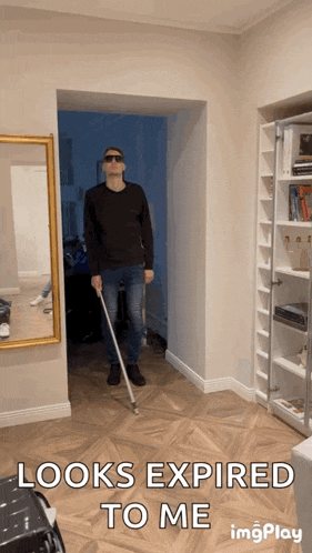 a man holding a cane in a hallway with the words looks expired to me below him