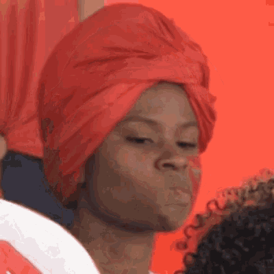 a woman wearing a red turban is blowing a kiss and making a funny face .