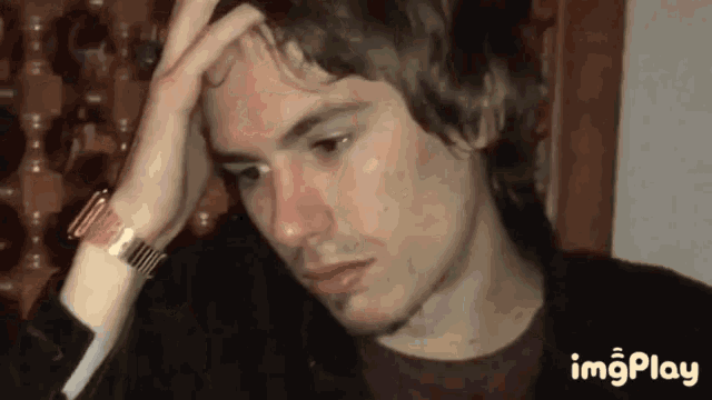 a man with a watch on his wrist is holding his hand to his forehead .