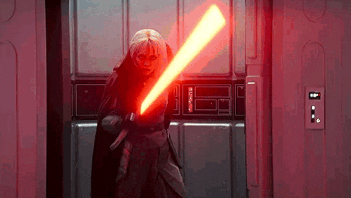 a woman is holding a red light saber in a room .
