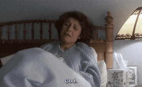 an elderly woman is laying in bed with a box of tissues and says god