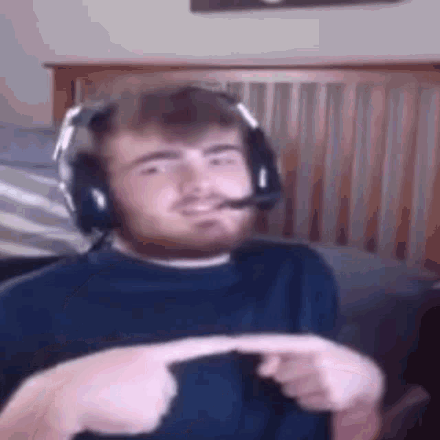 a man with a beard wearing headphones and a microphone is pointing at something .