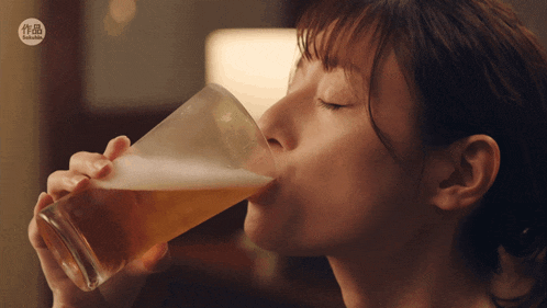 a woman is drinking a glass of beer with a sticker that says taiwan on it