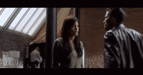 a man and a woman standing next to each other in a dark room