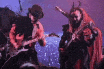 a man is playing a guitar while another man is playing a guitar on a stage .