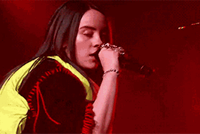 a woman is singing into a microphone while wearing a neon jacket .