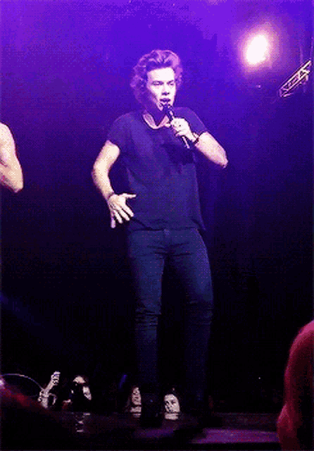 a man in a black shirt is singing into a microphone
