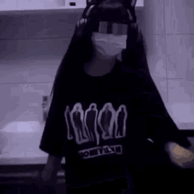a girl wearing a mask and a cat ear headband is standing in a kitchen .