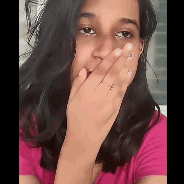a woman with a ring on her finger covers her mouth